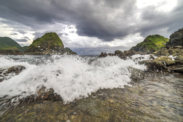 Natural rock with strong water wave and cloudy sunset background at Pantai Semeti Lombok, Indonesia.