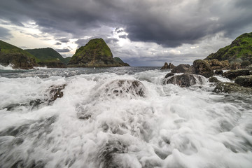Natural rock with strong water wave and cloudy sunset background at Pantai Semeti Lombok, Indonesia.