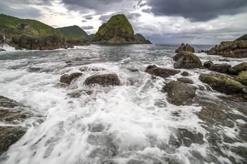 Obraz premium Natural rock with strong water wave and cloudy sunset background at Pantai Semeti Lombok, Indonesia.