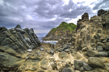 Natural rock with strong water wave and cloudy sunset background at Pantai Semeti Lombok, Indonesia.