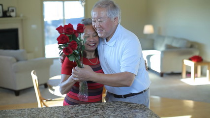 Senior man giving flowers to wife - Powered by Adobe