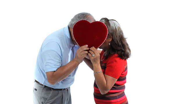 Senior couple kissing behind heart