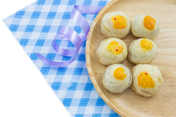 Chinese Pastry Mung Bean or Mooncake with Egg Yolk on wooden dish and spoon striped cloth ribbon