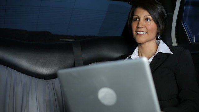 Woman typing on laptop inside limo