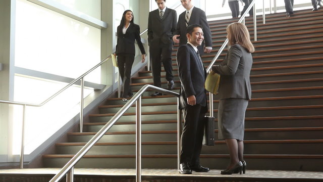Businesspeople meet on steps of lobby