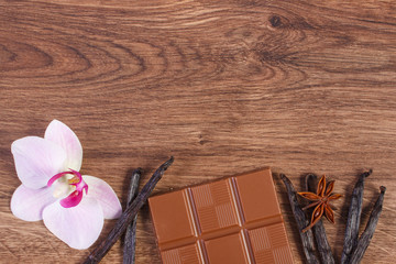 Milk chocolate, fragrant vanilla sticks and blooming orchid, copy space for text