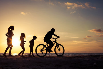 Fototapeta premium Father and children playing on the beach at the sunset time.