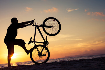 happy man with bicycle standing on the beach