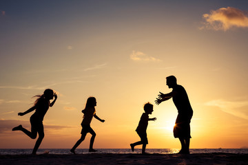Fototapeta na wymiar Father and children playing on the beach at the sunset time.