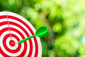 Green darts arrows in the target center on green bogeh backgroun