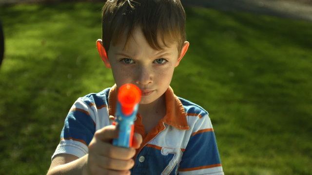 Young boy shooting toy gun at camera