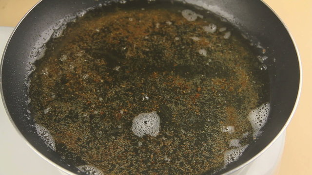 Taking a cooked fried fillet of crumbed fish with tongs out of a pan.