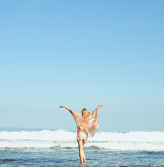Portrait of young woman looking at the ocean with hands up