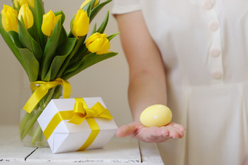 Beautiful woman with a gift and fresh yellow tulips. Easter.