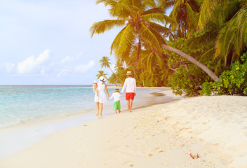 family with two kids walking at tropical beach