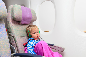 little boy with headset watching tv in flight