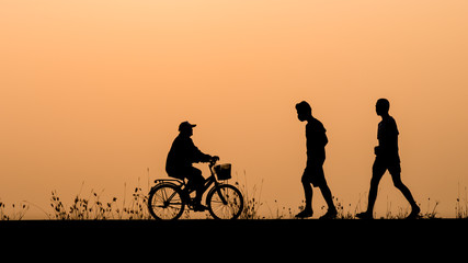 Silhouette of people cycling and walking relax