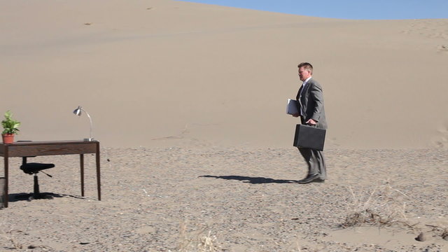 Businessman in desert walks to desk