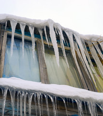 Long icicles hanging from the roof of  house.