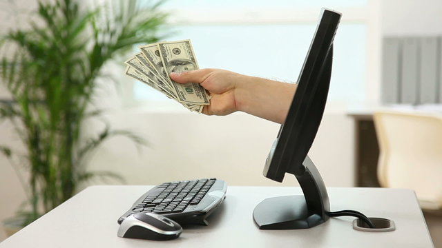 Hand with money sticks out of computer screen