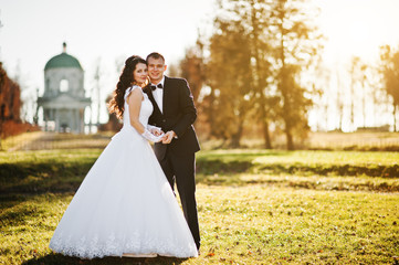 Fashionable wedding couple at sunny day background old church