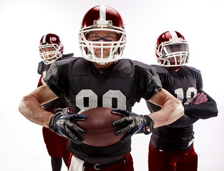 The three american football players posing with ball on white background