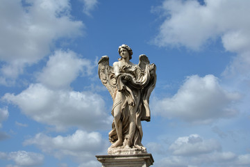 Fototapeta na wymiar Angel with Garment and Dice from Ponte Sant'Angelo in Rome, with heavenly sky and clouds