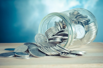 Coins spilling out of a glass bottle with filter effect retro vi