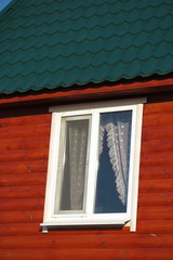 Fototapeta premium Plastic window of a modern summer cottage with the green tiled roof