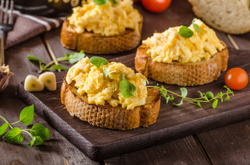 Scrambled eggs with herbs and garlic on toasted bread