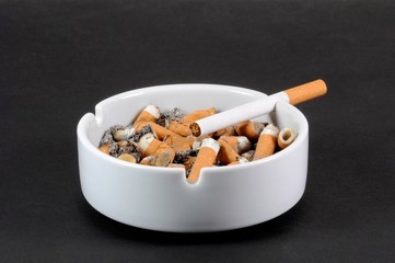 White ceramic ashtray full of smokes cigarettes