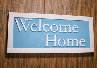 Framed welcome home sign on clean wood panel wall.