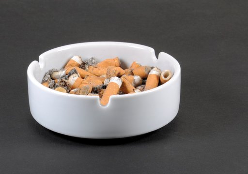 White ceramic ashtray full of smokes cigarettes