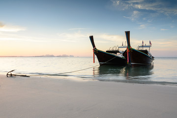 Two wooden boats on a beach at sunrise time