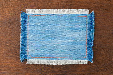 Frame for the text from a blue jeans fabric with the stitched lines of an orange thread and fringed