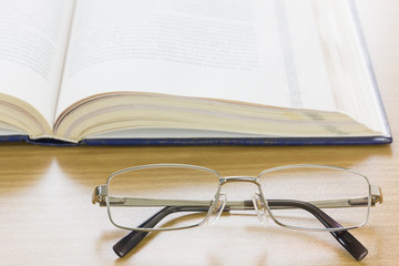 Close up glasses and a book on the desk