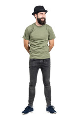 Bearded man wearing hat and t-shirt laughing carefree with eyes closed. Full body length portrait isolated over white studio background.