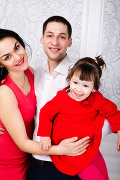 Happy elegant family with baby girl in studio