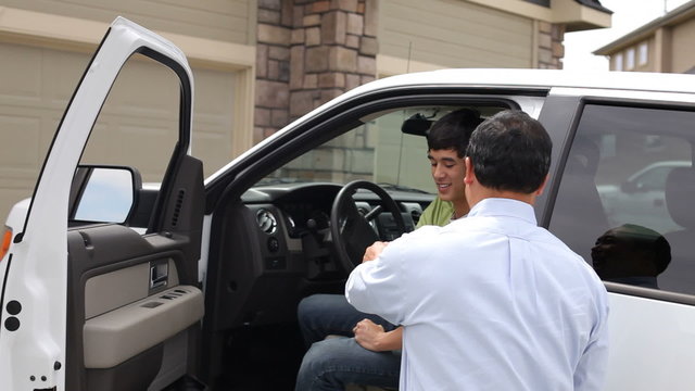 Father congratulates son as he gets into new truck
