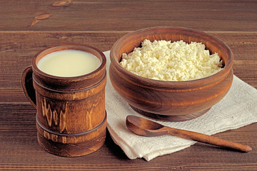  Milk and cottage cheese.   Milk and cottage cheese in a wooden cookware on a brown wooden background.
 