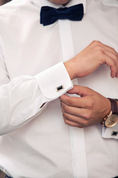 man dresses cuff links on shirt cuffs