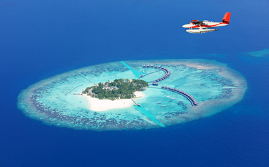 Sea plane flying above Maldives islands - obrazy, fototapety, plakaty