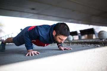 Young man doing push-ups after workout and jogging.