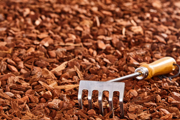 Small garden rake on wood chip pile