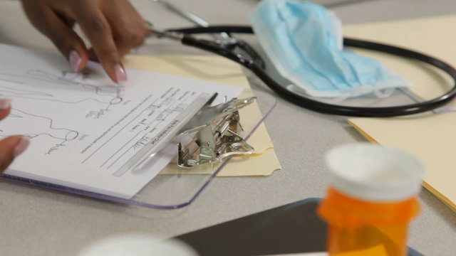 Nurse fills out medical paperwork, closeup
