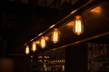 Decorative antique edison style light bulbs arranged in a row. Selective focus.