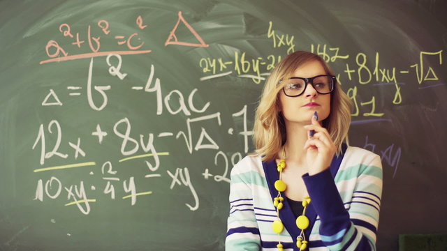 Thoughtful teacher standing next to the blackboard
