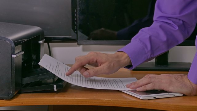 businessman  man in office prints examines documents on printer typing on tablet