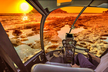 Helicopter Cockpit on the reef at sunset, with pilot arm and control board inside the cabin. Monemvasia castle, Peloponnese, Greece at sunrise.