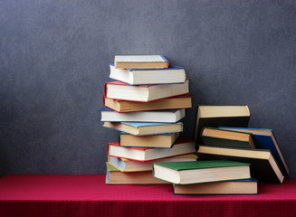 A stack of books on the table with a red tablecloth.